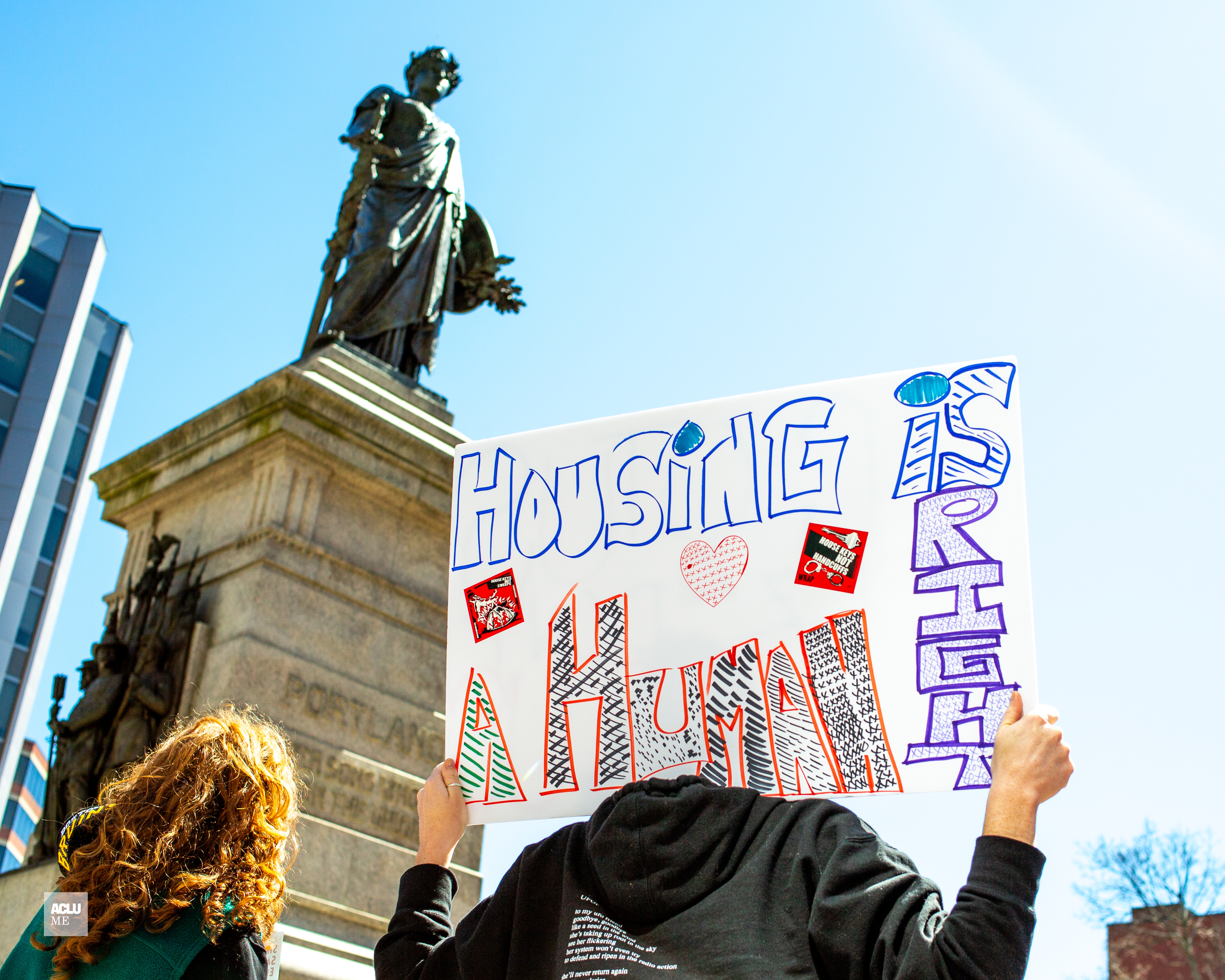 Person holding poster reading "housing is a human right."