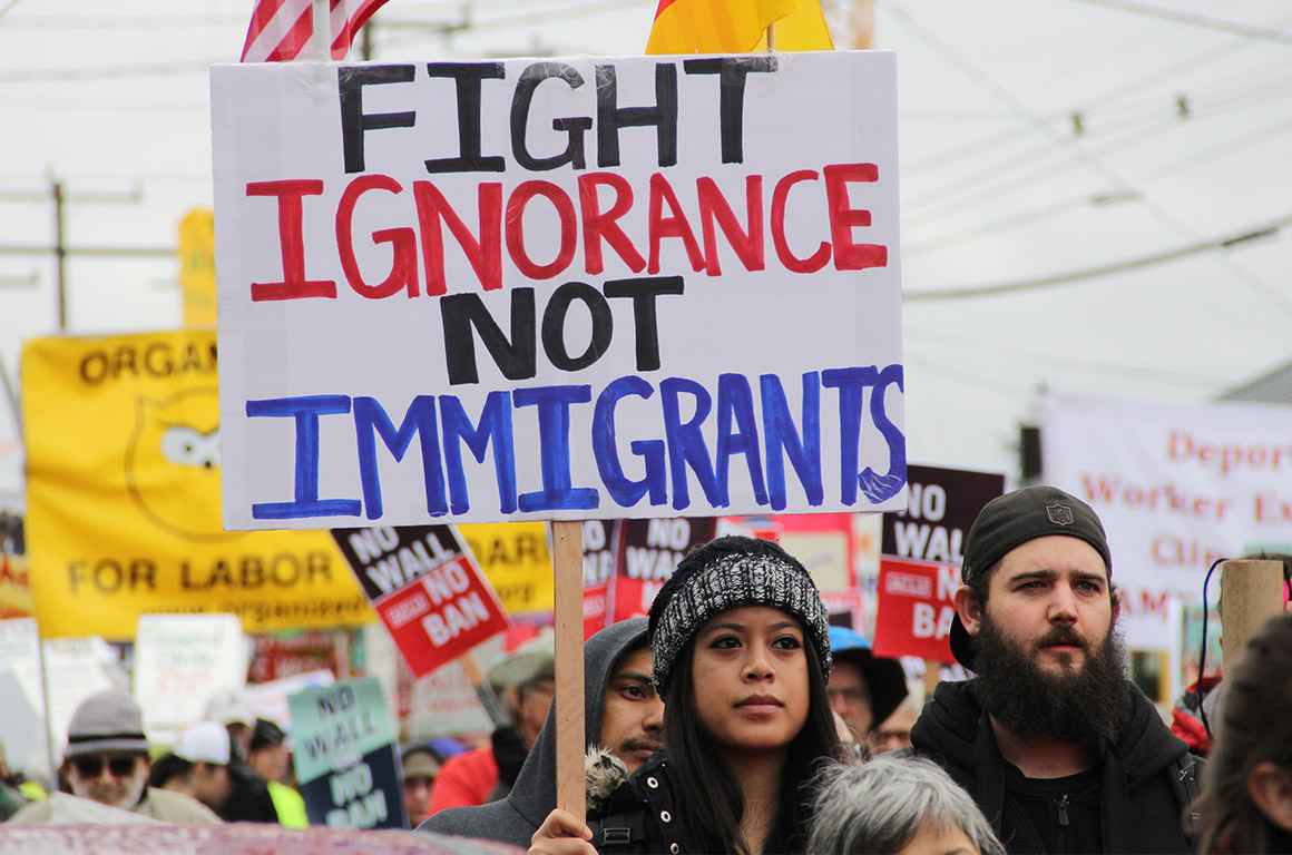 A protester holding a sign with the text &quot;fight ignorance not immigrants&quot;