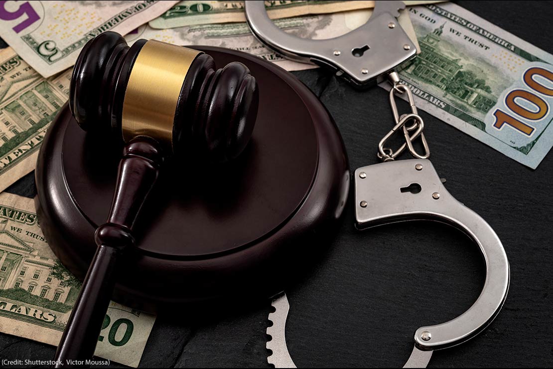 A gavel and a pair of handcuffs on a pile of money.